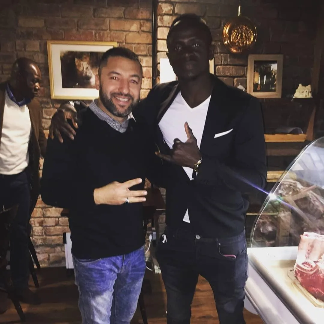 Okan Events host with a guest beside a premium meat counter