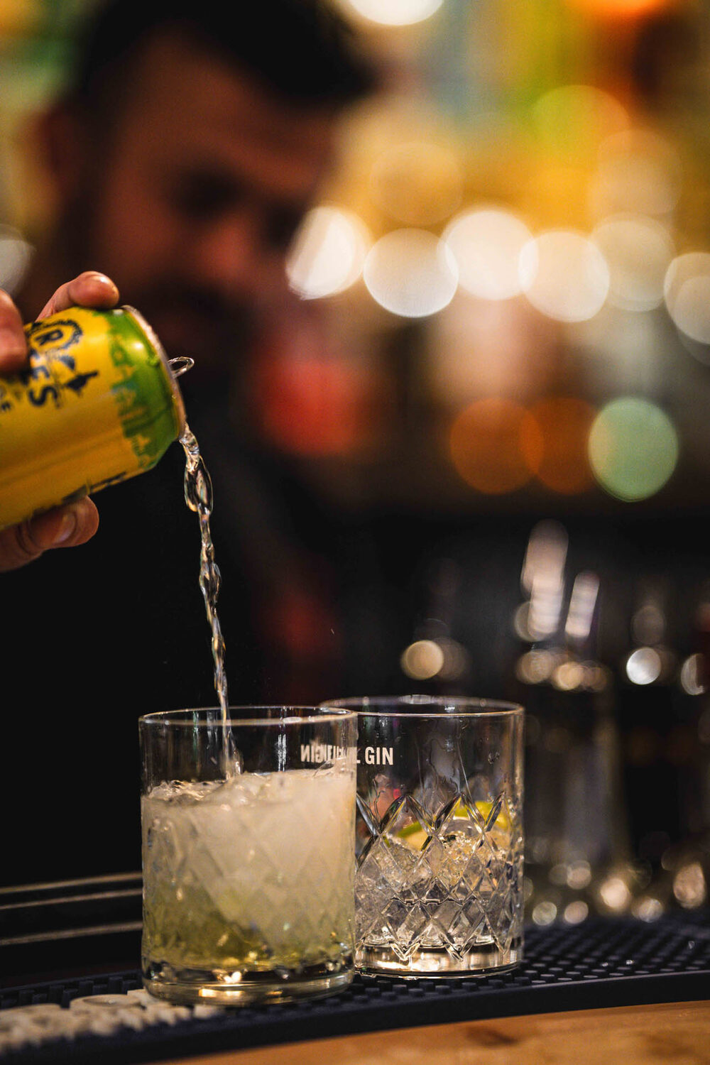 Bartender pouring a drink into a crystal glass at a dimly lit bar
